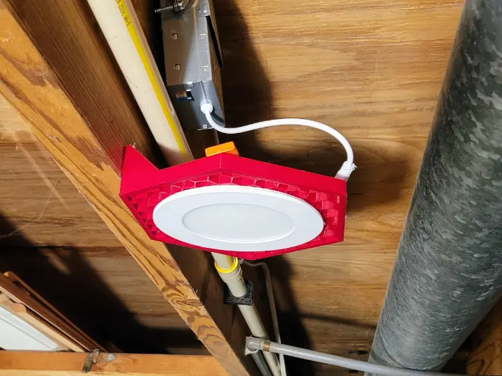 3D printed bracket installed in joist in unfinished basement.