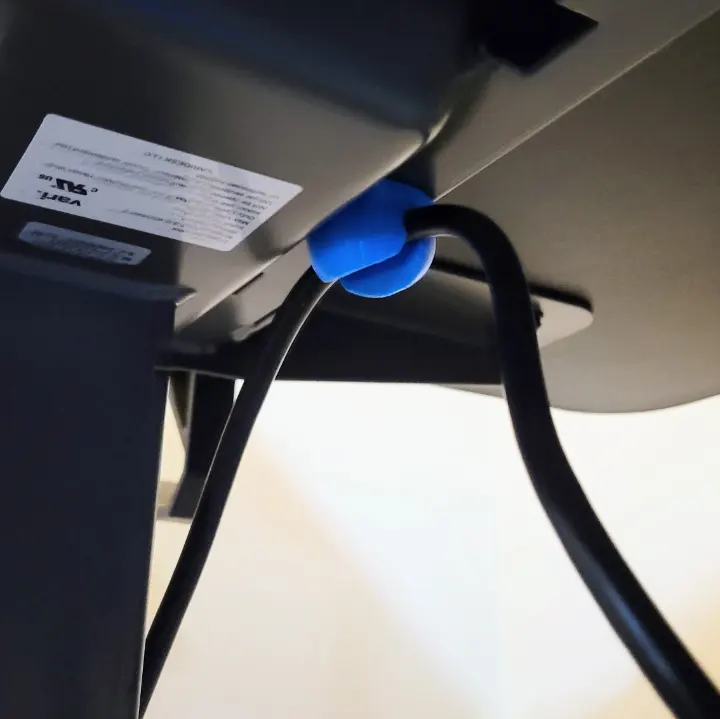 A customizable 3D printed magnetic cable holder holding a cable under a desk.